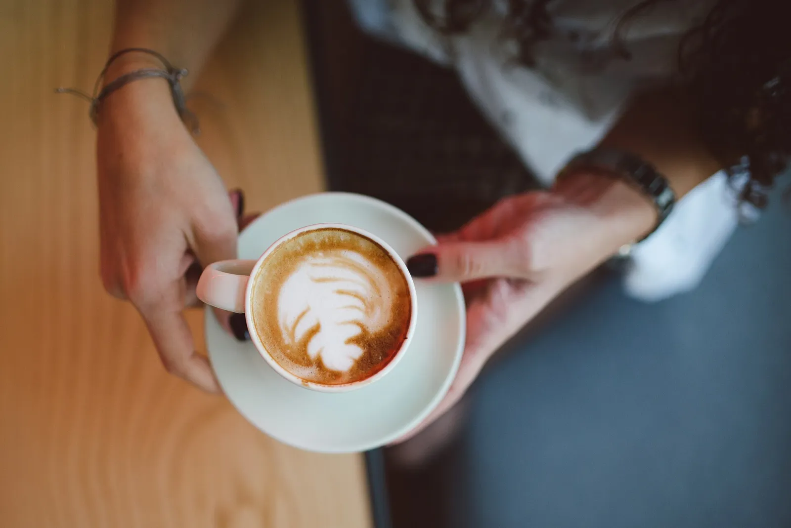 A cappuccino with latte art at a cafe table. The photo was not taken in Boynton Beach.